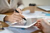 a person using the backside of their pen to point at a tablet screen that is being shown to them